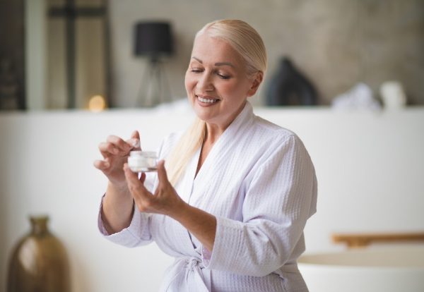 Face care. Cute mid aged woman with a jar of face cream