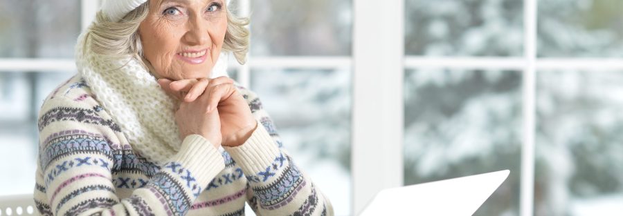 - seguridad invierno mayores pensilvania - senior woman using laptop sitting near window - home care concepts - home care